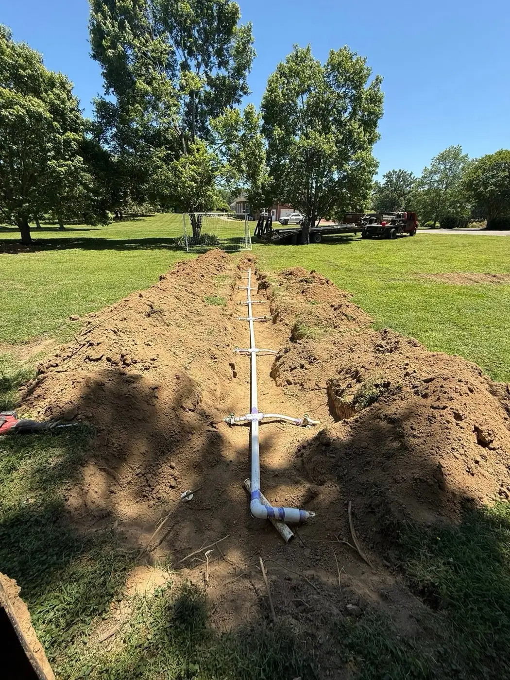Drain field manifold piping connected in an open trench