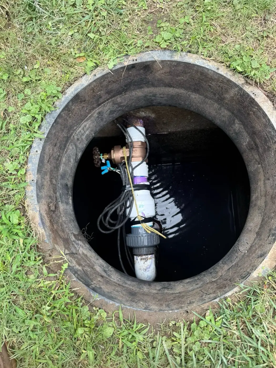 Inside of a septic pump chamber with the pump and wiring visible
