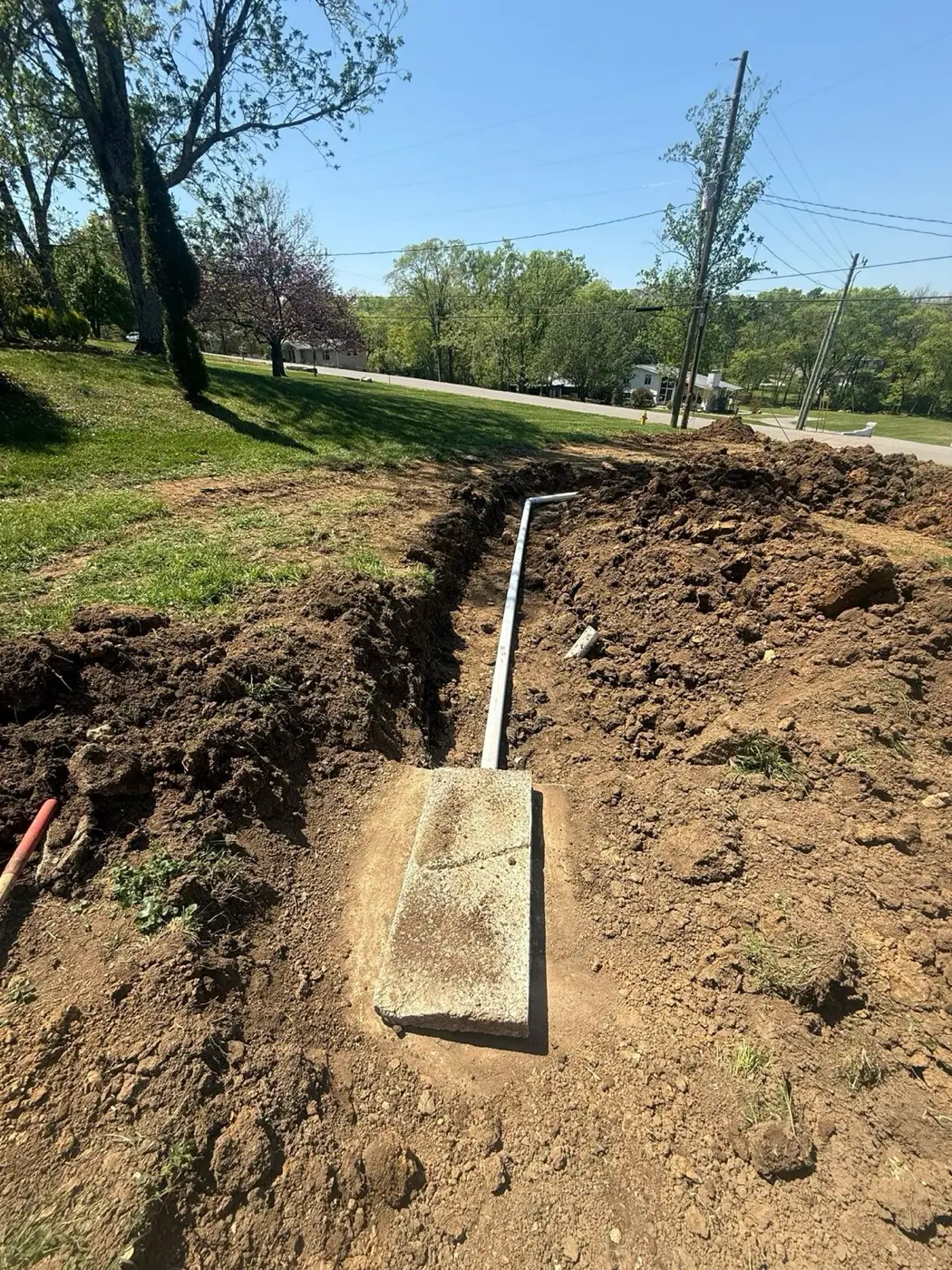 Water line and conduit set in a trench beside a house